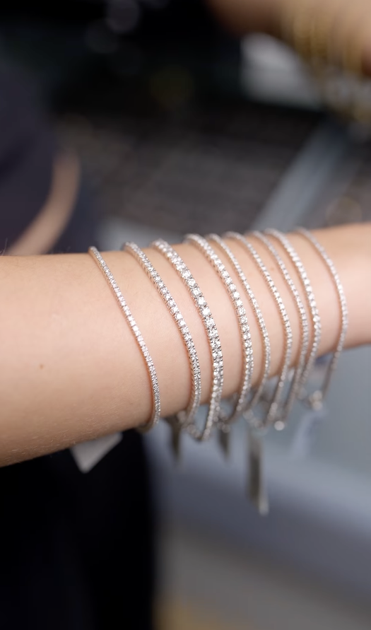 Flere fine sølv-armbånd med diamanter præsenteret på kundens arm.